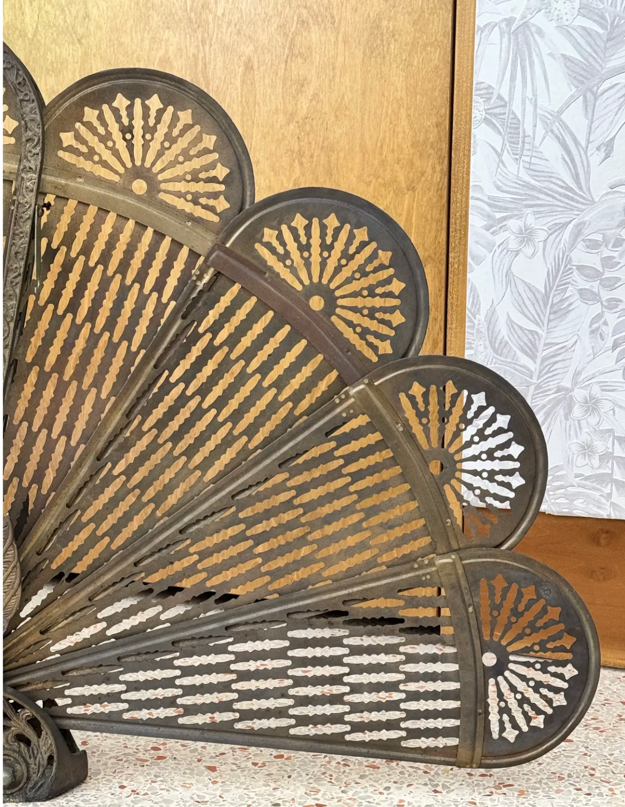 Articulated brass peacock screen displayed beside a fireplace