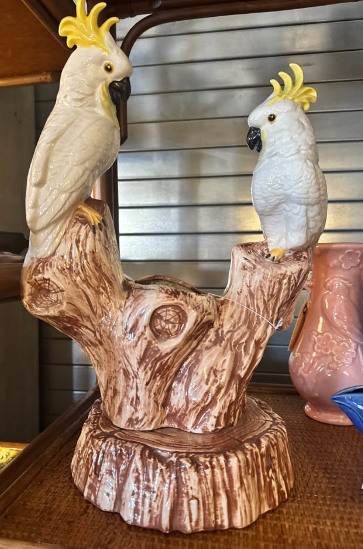 Two white ceramic cockatoos perched on a faux-bois tree stump