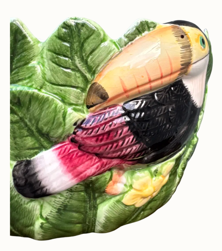 Hand-painted ceramic toucan surrounded by tropical leaves